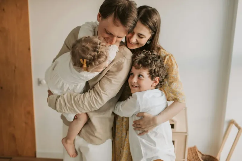 Family of four hugging at home